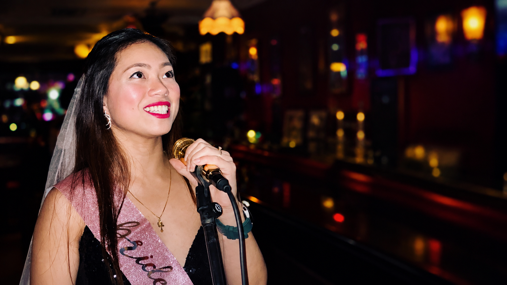 A guest wearing a Bride sash singing at London Karaoke Club